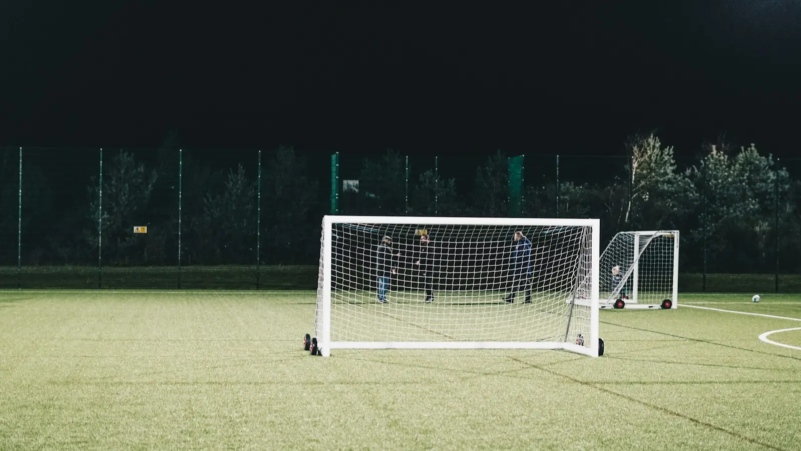 Voetbaldoelen op een sportveld in de avond, verlicht door veldverlichting